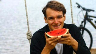 Andrew Perlot holds a watermelon while sitting on a swing