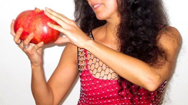 Eva Fruit looks at a large pomegranate she holds