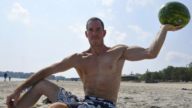 Korey Constable holds a large watermelon on a beach