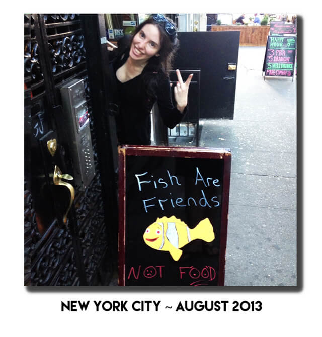 Jenny Lapan gives a peace sign behind a "Fish Are Friends" sign in New York City