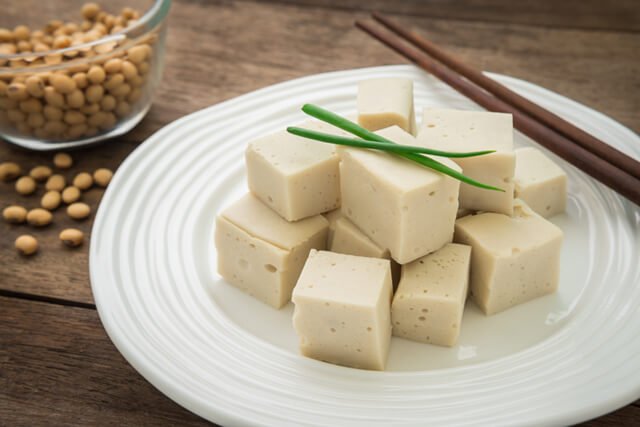 Tofu cubes on a plate and soybeans in a bowl