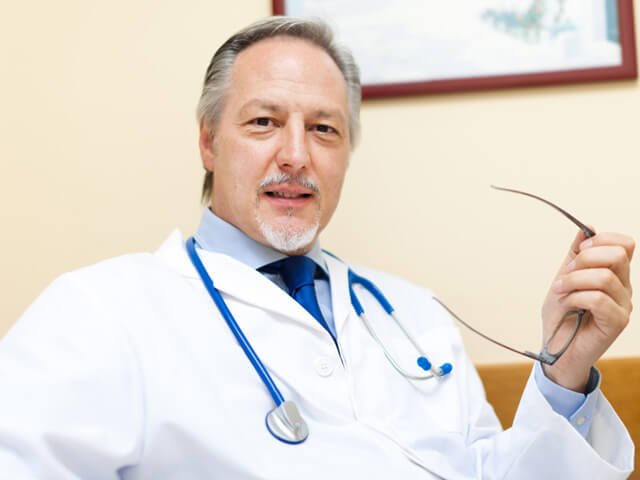 A doctor holds his glasses