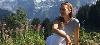 Amy Yuter sits on a hillside with mountains in the background