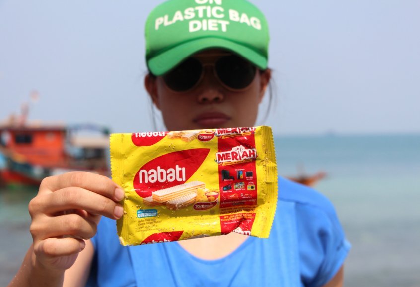 Tiza Mafira holding single-use plastic wrapper - effects of plastic on environment - Fruit-Powered
