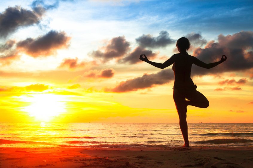Woman practicing yoga on beach - Fruit-Powered