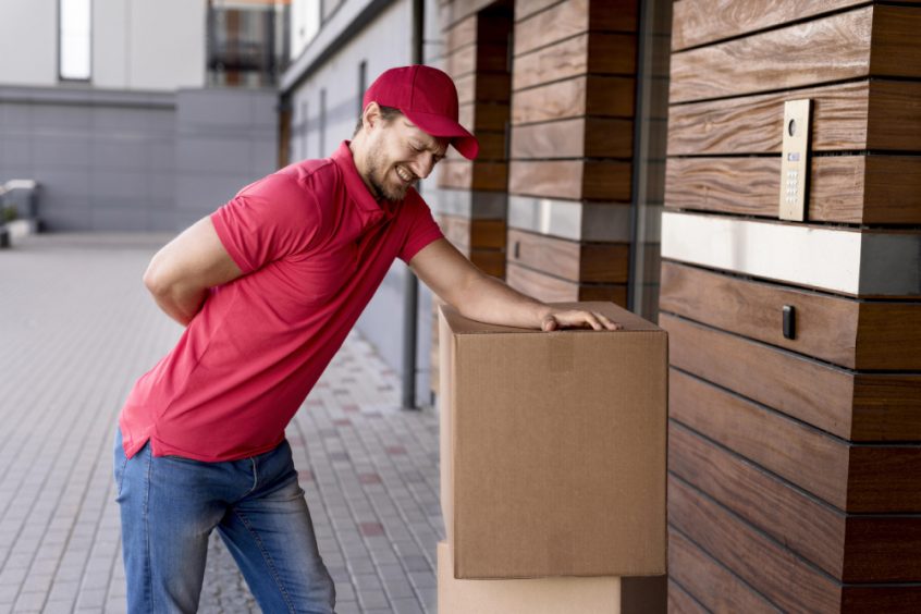Delivery man suffering from back pain while carrying box - Fruit-Powered